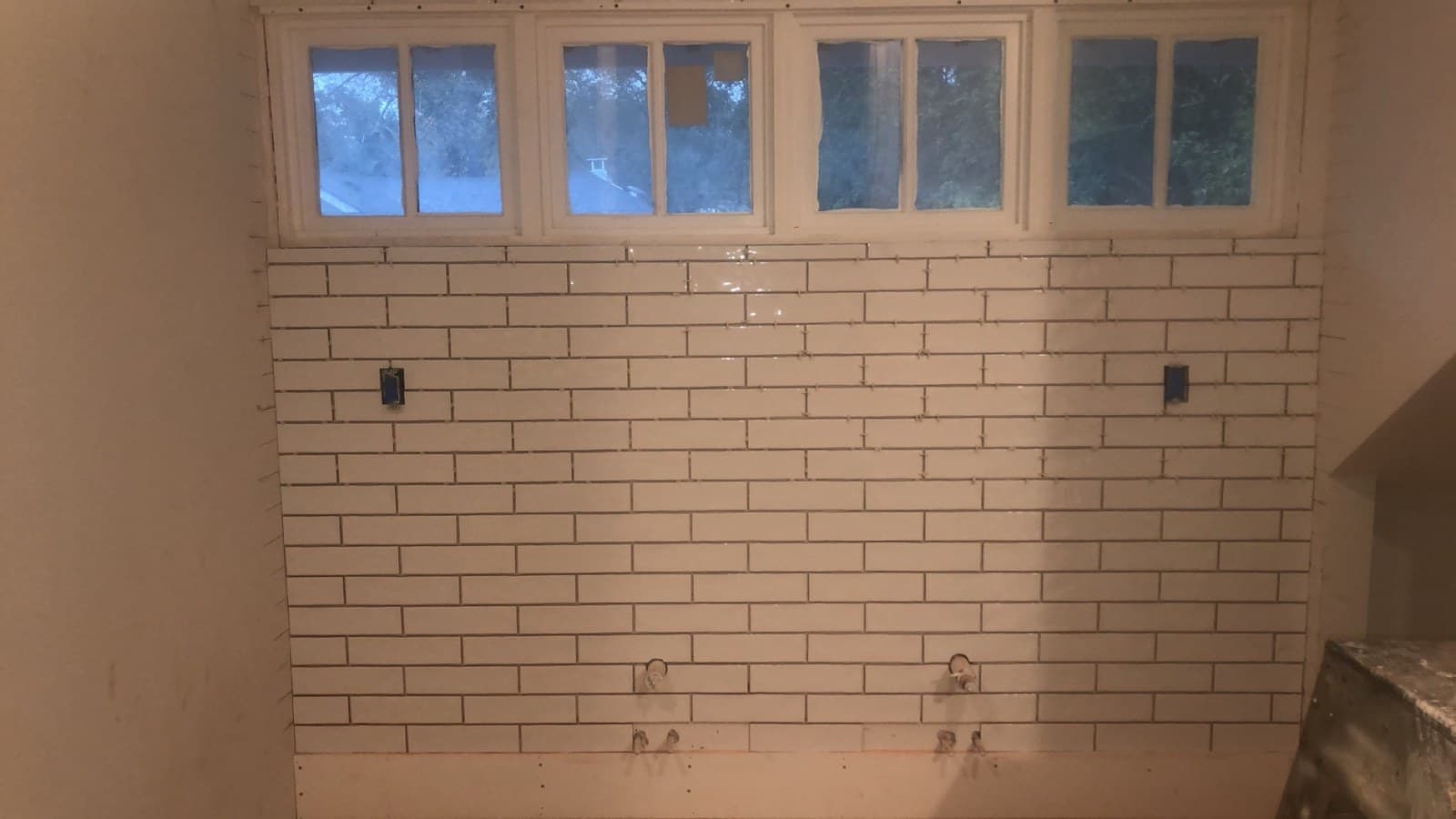 White subway tile going up beneath a row of transom windows